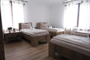 a room with three beds and a table and windows at Casa Pelerinului in Bogata