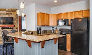 une cuisine avec un réfrigérateur noir et des armoires en bois dans l'établissement Beautiful Resort in Glacier Canyon 2BD Deluxe near Circus World, à Baraboo