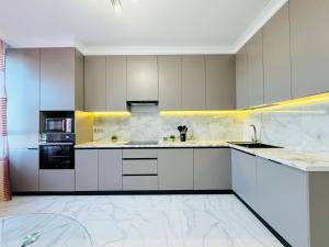 a large kitchen with white cabinets and appliances at 1835 Rams City Mountain View Apartment in Almaty +12 photos