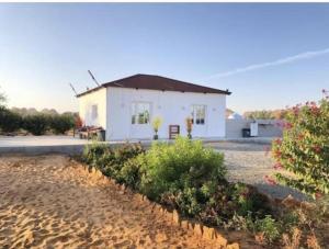 a small white house on a beach with bushes at Studio overlooking pool amid flowering and quiet in Al-ʿUla