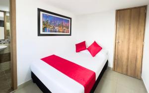 a bedroom with a white bed with red pillows at Hotel Los Angeles in Calarcá