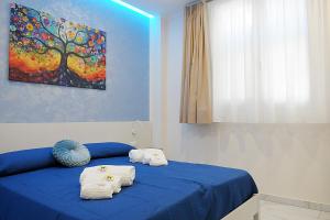 a bedroom with a blue bed with towels on it at B&B AIDA Rooms Cefalù in Cefalù