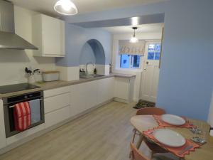 a kitchen with white cabinets and a table and a dining room at Abacus Cottage in Whitwell on the hill
