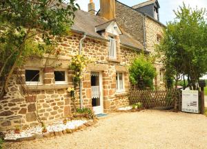 an old stone house with a sign in front of it at Camping Duguesclin in Saint-Coulomb