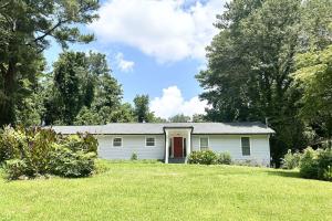a white house with a red door in a yard at Indian Lakes in Stone Mountain