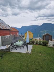a patio with a table and a umbrella on the grass at Feriehus ved fjorden i Solvorn in Luster