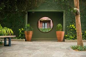 a circular mirror on a green wall with potted plants at Pauli Boutique Hotel in Fortaleza