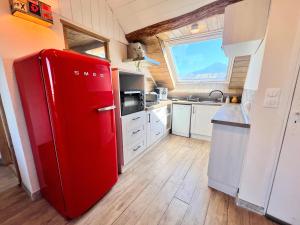 a red refrigerator in a kitchen with a window at appartement centre ville in Embrun +5 photos