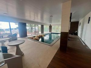 sala de estar con piscina, mesa y sillas en Fantástico Flat no Serra Class em Canela-RS, en Canela