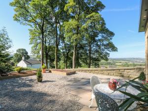 a patio with a table and chairs and trees at Priestleys Retreat in Blackburn