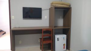 a room with a book shelf with a tv and a desk at Alliance Hotel in Bauru