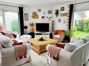 a living room with white couches and a tv at Villa CLOTESS in Dompierre-sur-Mer