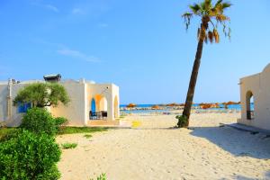 a palm tree and a house on the beach at Bungalow de Luxe en Bord de Mer a Nabeul in Bin Rhilouf