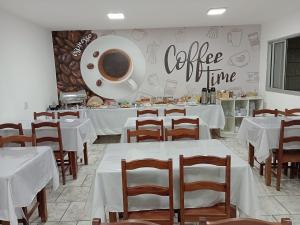 a restaurant with white tables and chairs and a coffee shop at Alliance Hotel in Bauru