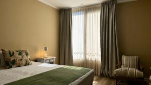 a bedroom with a bed and a window with a chair at Gardi Hotel & Suites in Buenos Aires