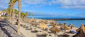 Una playa con sillas y sombrillas y el océano. en Take It EaSea, en San Miguel de Abona