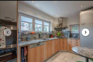 a large kitchen with wooden cabinets and stainless steel appliances at schönes Haus 5 separates Zimmer mit Sauna in Bonstetten