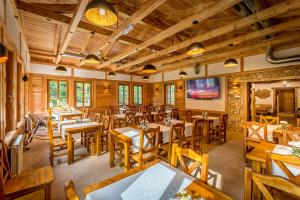 a restaurant with wooden tables and wooden chairs at Willa Orle Gniazdo in Biała Woda