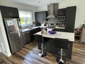 a kitchen with a stainless steel refrigerator and a counter at Le Fontainebleau - Magnifique chalet sur le bord de l’eau in Labelle +15 photos