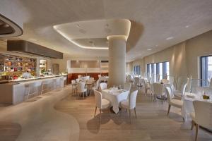 a restaurant with white tables and chairs and a counter at Mandarin Oriental, Doha in Doha