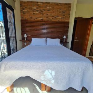 a large white bed in a bedroom with a brick wall at Habitaciones San Marcos 3 in Tequila