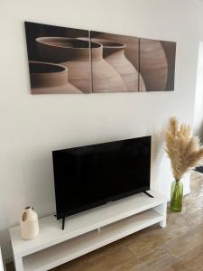 a flat screen tv sitting on a white stand in a living room at Jolie petite maison in Saint-Vaast