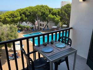 una mesa en un balcón con vistas a la piscina en Vistas al mar y la piscina, en Arenal d'en Castell