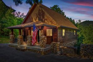 a log cabin with a flag in front of it at Pvt Pool at The Grotto in Sevierville