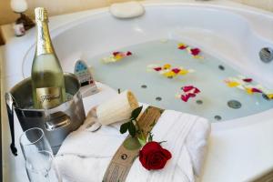 a bottle of champagne and a rose in a bath tub at Villas Mamma Mia pool heat Private & Jacuzzi in Playa Blanca