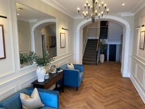a living room with two blue chairs and a chandelier at Number 9 Croft House Tenby in Tenby