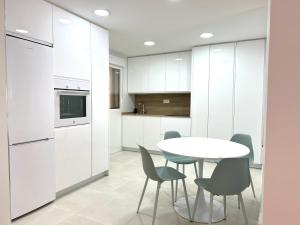 a kitchen with white cabinets and a table and chairs at La Klamma in Zamora