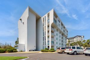 Un edificio blanco con coches aparcados en un estacionamiento. en Dolphin Point 702A, en Destin