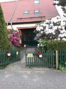 une clôture verte devant une maison fleurie dans l'établissement Harzglück, à Thale