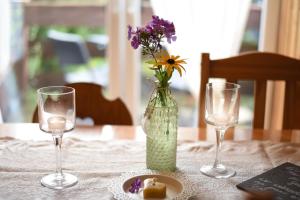 a vase with flowers in it on a table with two glasses at Harzglück in Thale