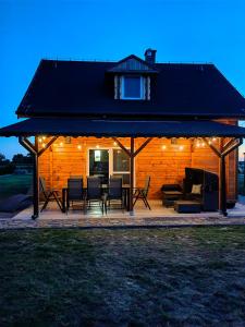 a pavilion with chairs and tables on a patio at Pałuckie Chaty duży domek z balia i sauną malownicza okolica in Łysinin