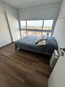ein Schlafzimmer mit einem Bett und einem großen Fenster in der Unterkunft Vista al horizonte in Mariano J. Haedo