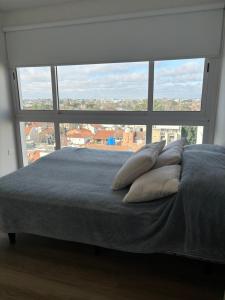 Bett mit Kissen vor einem großen Fenster in der Unterkunft Vista al horizonte in Mariano J. Haedo + 6 Fotos