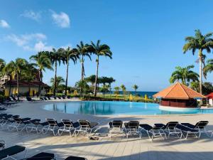 - une piscine avec des chaises longues, des palmiers et l'océan dans l'établissement Appartement, 2 chambres, Terrasse vue mer, très calme, Piscine premium, accès direct aux plages, restaurants, Village Vacances, à Sainte-Luce