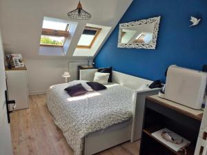 a bedroom with a bed and a blue wall at Les Charmilles in Escoville