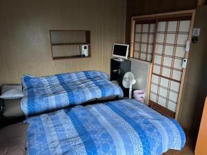 直島町にある一日限定一組の古民家の宿なんでもんのベッドルーム(青い掛け布団、テレビ付)