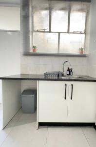 a kitchen with white cabinets and a sink and a window at Studio at Illovo Mews in Sandton
