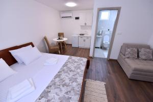 a bedroom with a bed and a couch and a kitchen at Airport Apartments TRI HRASTA in Podgorica