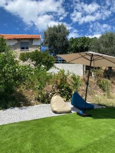 a tent and an umbrella on the grass at Casa de Pedra em Vinha no Dão in Nelas