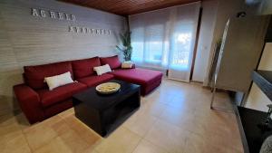 salon z czerwoną kanapą i stołem w obiekcie Apartamento AGRELO w mieście Bueu