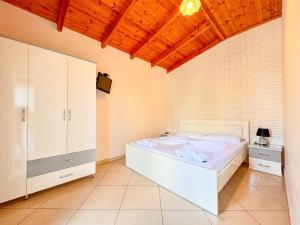 a bedroom with a white bed and a wooden ceiling at Zace Studios in Ksamil