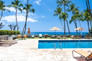 een zwembad met palmbomen en de oceaan bij Elua 704 in Wailea
