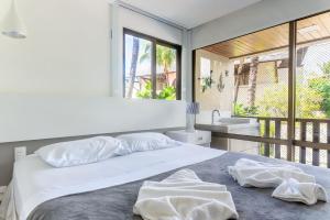 ein weißes Schlafzimmer mit einem Bett und einem Waschbecken in der Unterkunft Nannai Residence Muro Alto Porto de Galinhas por Brevelar in Porto De Galinhas