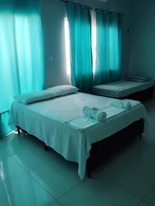 a bedroom with two beds with blue curtains at Pousada do Bosque-Hostel in Rio Branco