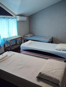 a room with three beds and a table at Pousada do Bosque-Hostel in Rio Branco