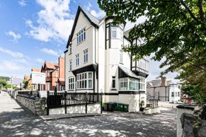 a large white house with a black fence at Roomours Hotel with Private Car Park in Llandudno